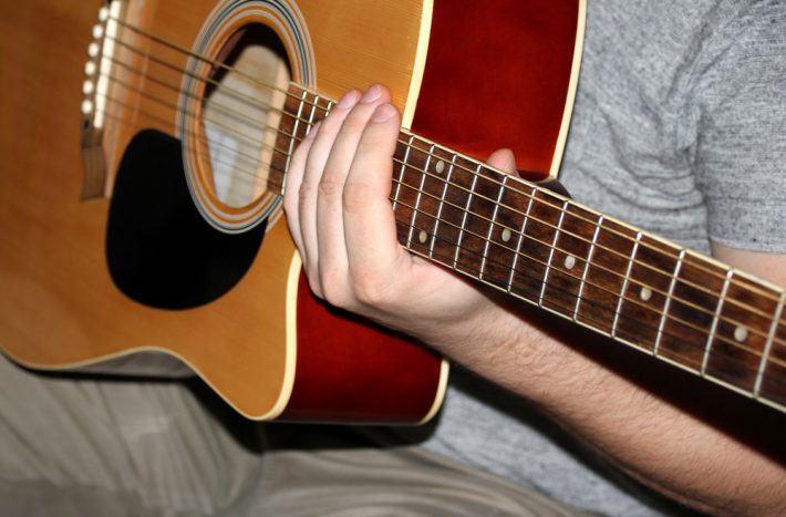 muž drží kytaru