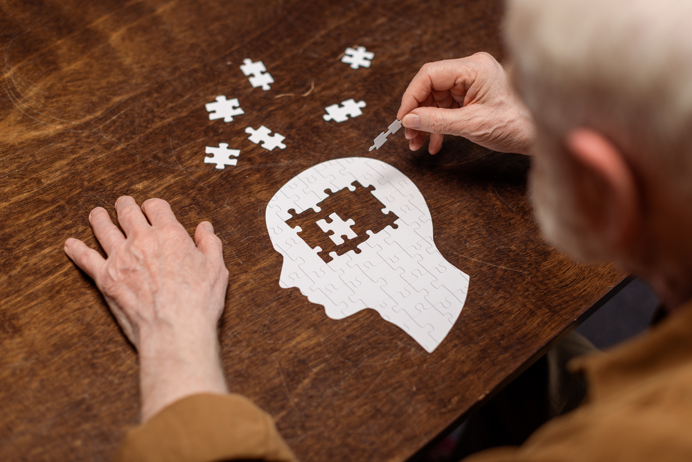 muž skládá puzzle ve tvaru mozku, Alzheimer