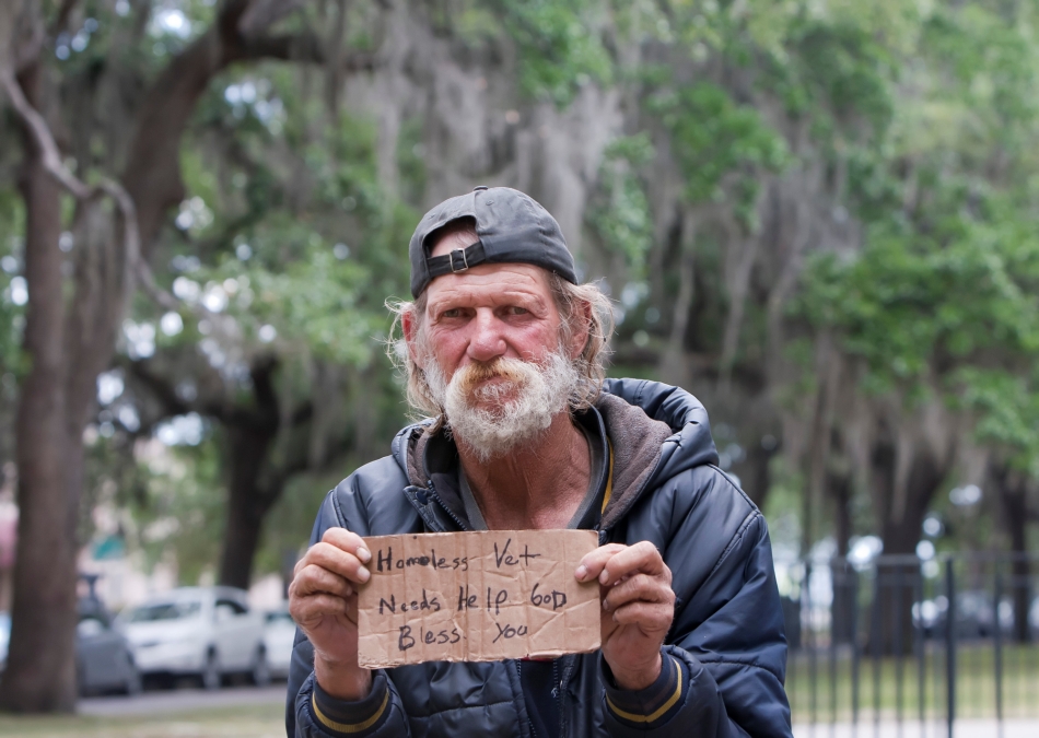 Bezdomovec drží nápis