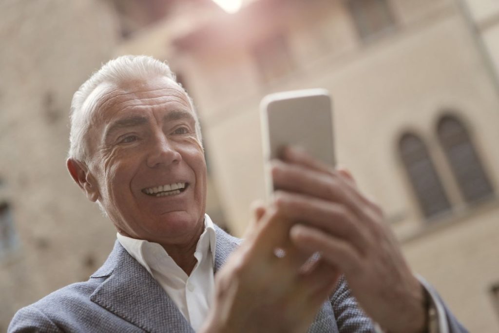 starší muž se usmívá při pohledu na mobil