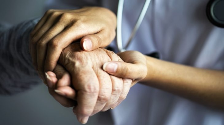 Zdravotní sestra drží za ruku pacienta