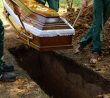 Pohřebáci spouštějí rakev do hrobu