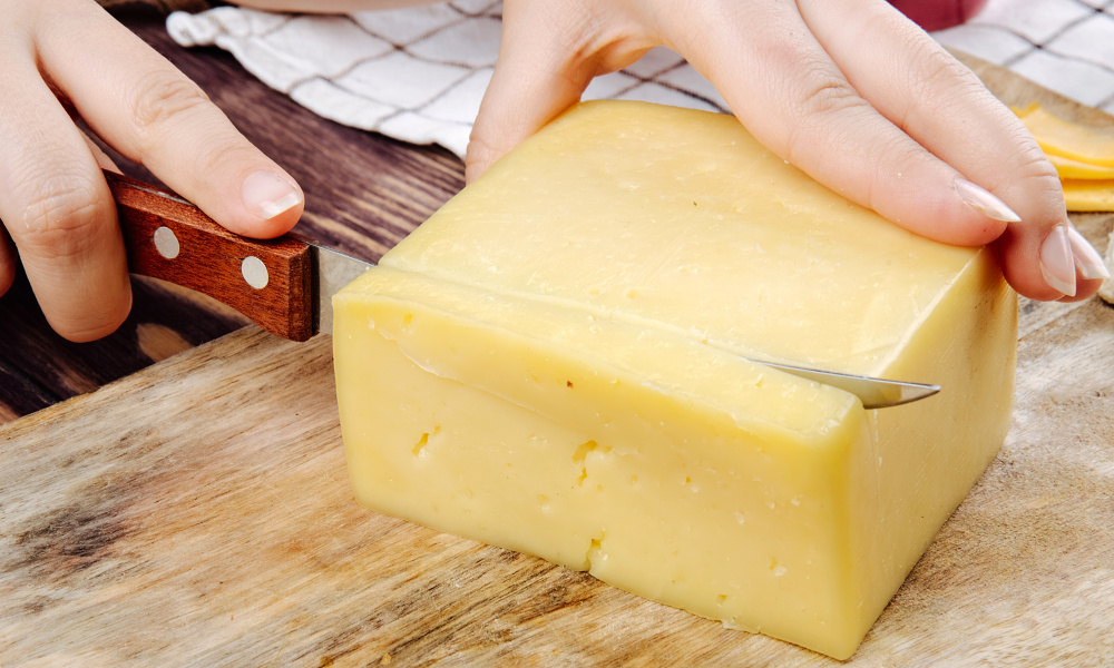 Žena krájí sýr na prkénku