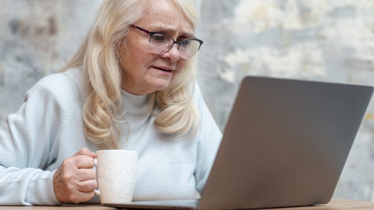 Starší žena pije kávu u notebooku