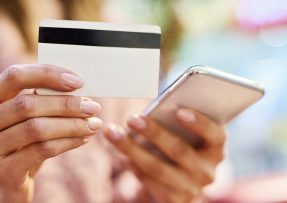 Ženské ruce drží mobil a platební kartu