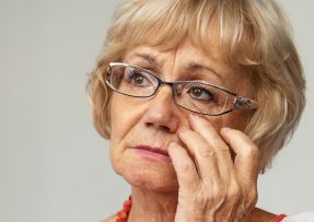 Smutná starší žena s brýlemi