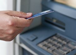 Ruka drží kartu u bankomatu