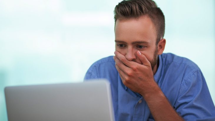 Zaskočený muž kouká do počítače