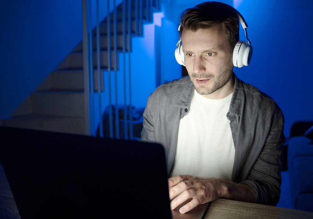 Muž se sluchátky kouká do počítače