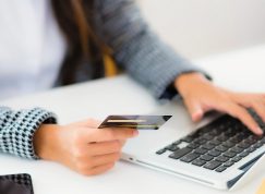 Ruka s platební kartou a notebook