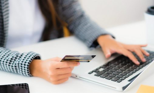 Ruka s platební kartou a notebook