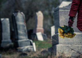 Žena nese květiny na hrob