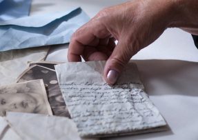 Ruka drží staré dopisy a fotografie