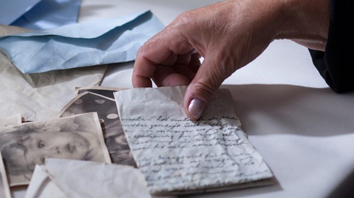Ruka drží staré dopisy a fotografie