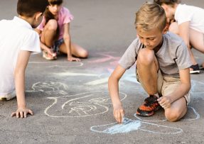 Děti malují křídou na chodník