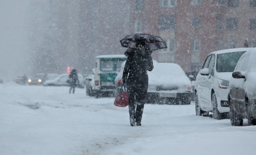 Žena s deštníkem jde ve sněhu